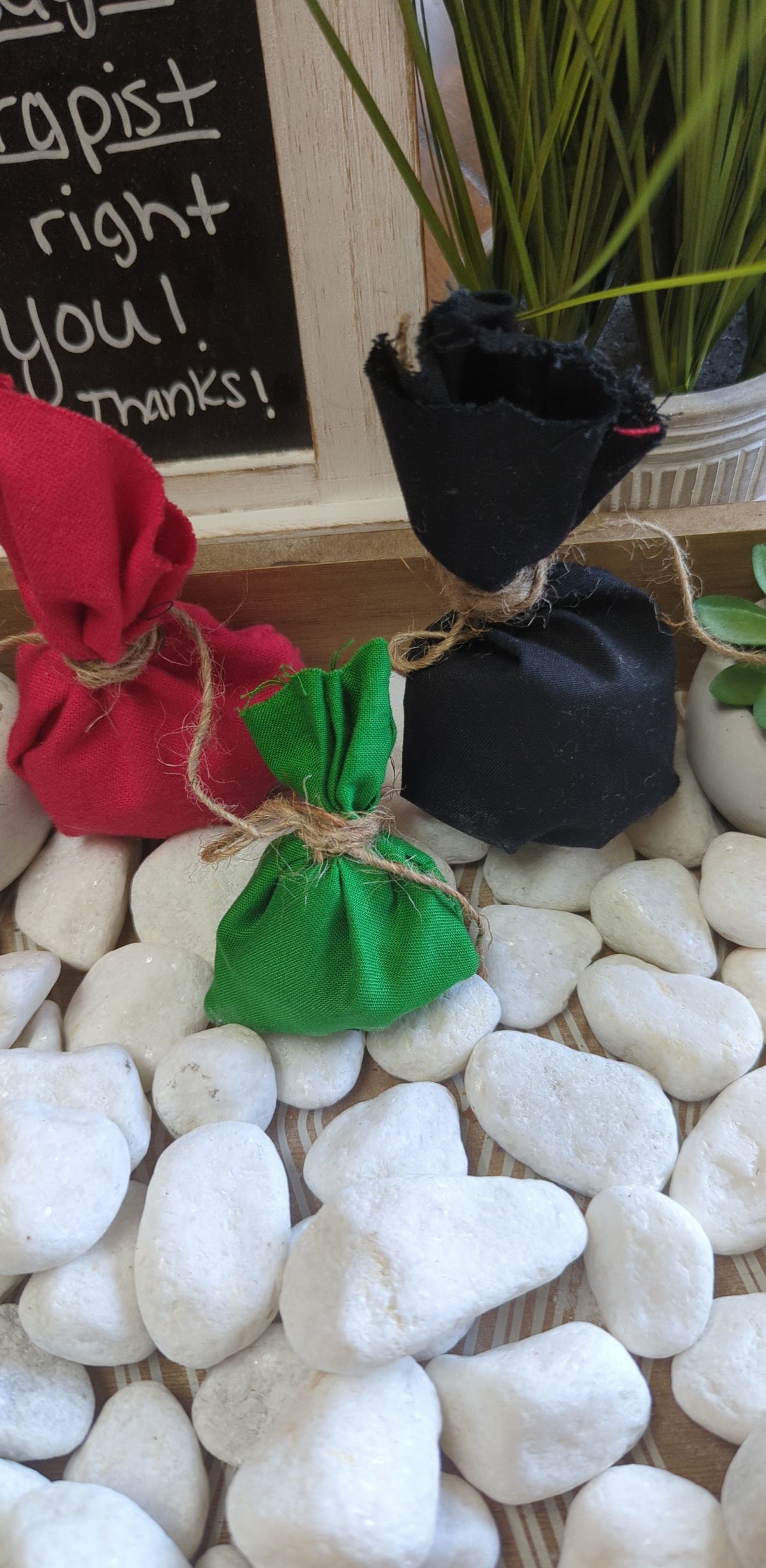 Protection Mojo Bag in red, green, and black, placed on white stones for shielding against negativity.